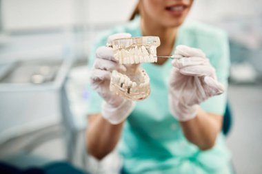Close-up of orthodontist showing dental prosthetic with one dental implant at dentist's office.