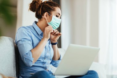 Young woman using laptop and learning online how to wear face mask properly during virus epidemic. 