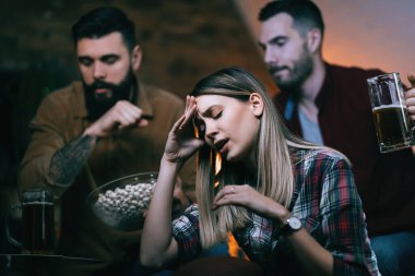 Group of disappointed sport fans feeling sad after their team has lost a game. Focus is on woman.