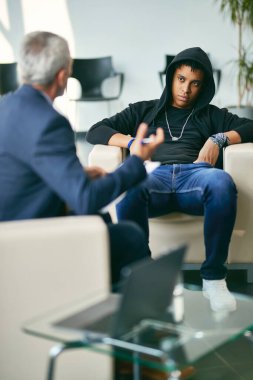 African American teenage boy having a session with mental health professional at counselling center.
