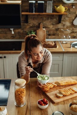 Genç mutlu kadın mutfakta yemek hazırlıyor ve avokado bruschetta yapıyor.. 