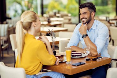 Happy man talking to his girlfriend while having dessert in a cafe. 