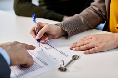 Close-up of woman signing agreement with insurance agent while buying new home with her husband. 