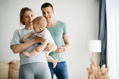Young family having fun while spending time together at home. Focus is on mother holding a baby.