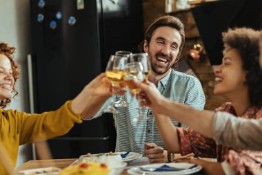 Young happy man having fun while toasting with his friends during lunch tome at dining table. 