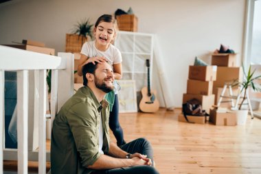 Playful father and daughter having fun while relocating in a new apartment. 