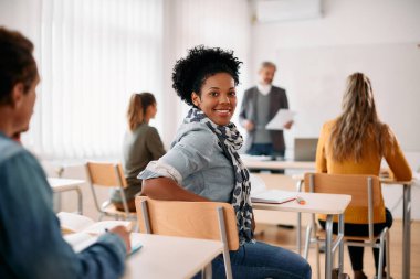 Happy African American woman attending lecture in the classroom and looking at camera.