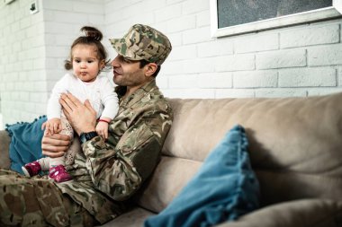Young happy military man spending time with his small daughter after coming home from war. 