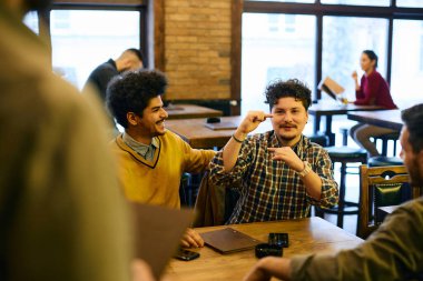 Young man gesturing while ordering drinks from waiter for his friends in a pub.
