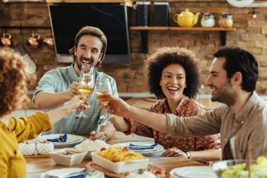 Group of happy friends toasting with wine and having fun while having a meal together at dining table. 