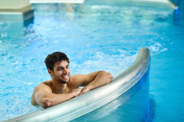 Happy man spending a day at the spa and enjoying in the swimming pool. 
