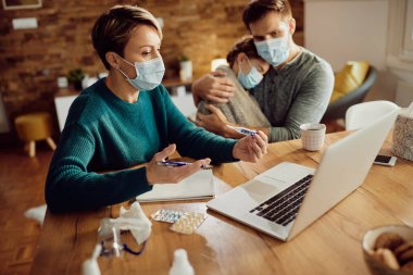 Caring mother having video call with a doctor and talking about daughter's fever during coronavirus pandemic. 