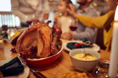 Close-up of Thanksgiving turkey on dining table with family in the background, 