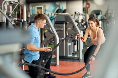 Spor salonunda antrenman yaparken halatlarla antrenman yapan genç atletik bir kadın..