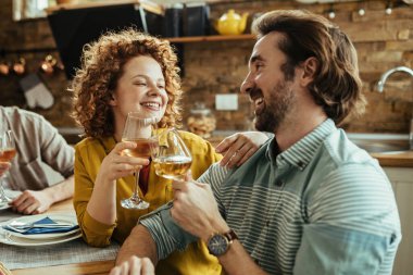 Smiling couple in love toasting with wineglasses while having lunch at home. 
