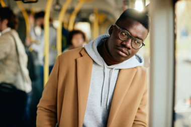 Young African American man looking through the window and thinking of something while traveling by bus. 