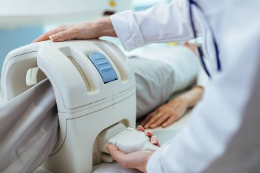 Close-up of doctor preparing her patient for knee MRI scan examination at clinic. 