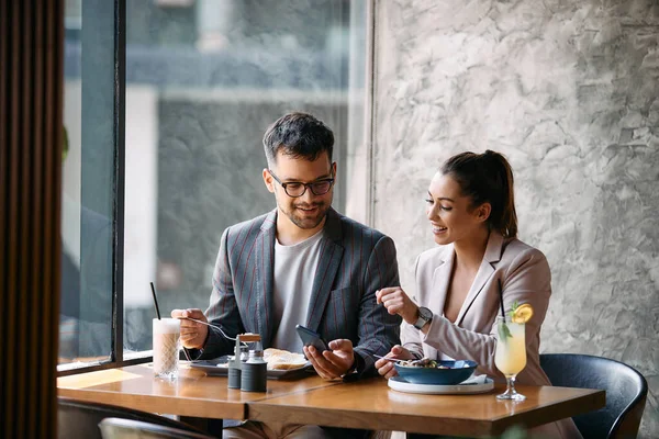 Happy Businessman His Female Colleague Using Mobile Phone While Eating —  Fotos de Stock