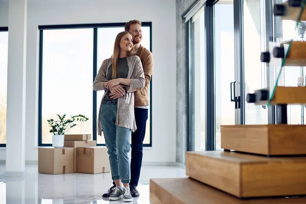 Full Length Happy Couple Embracing Looking Window Moving New Apartment — Fotografia de Stock