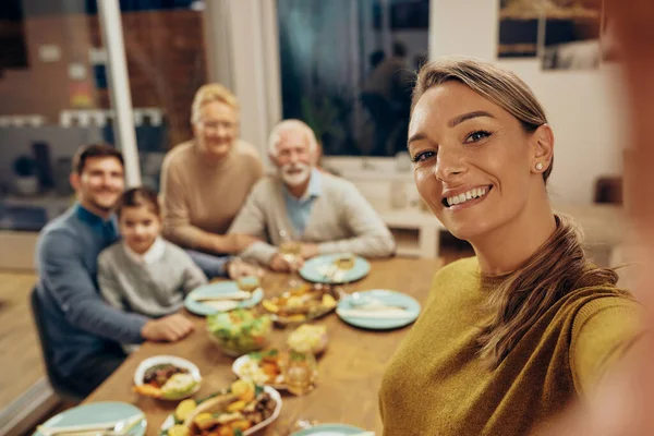 Happy family and her extended family taking selfie during lunch at home.