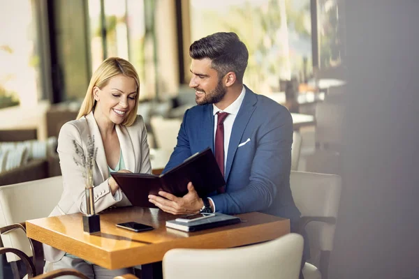 Happy business couple choosing an order from a menu while being in a restaurant. Copy space.