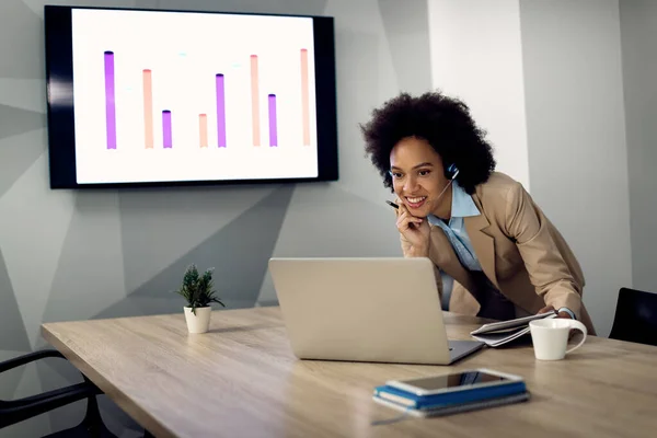 Happy black female entrepreneur using computer during conference call in the office.