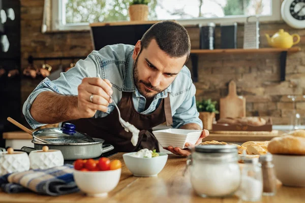 Genç şef yemek hazırlıyor ve bir kaseye sos döküyor.. 