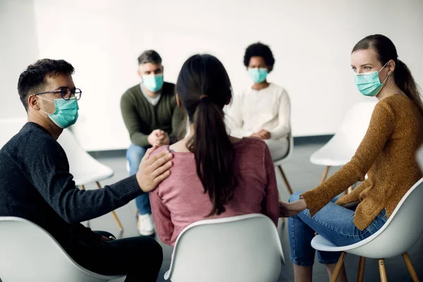 Group of people wearing face masks while participating in psychotherapy during coronavirus pandemic. 