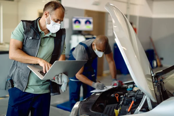 Car Repairman Working Laptop While Examining Engine Performance His Colleague — Stock fotografie