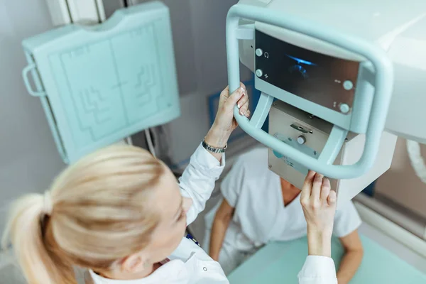 Close-up of medical technician adjusting X-ray machine for patient examination in the hospital.