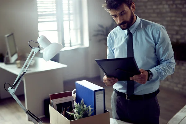 Young entrepreneur feeling sad while looking at picture in photo frame after being fired at work.