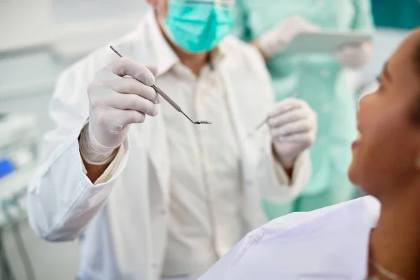 Close-up of dentist examining teeth of African American woman at dentist\'s office.