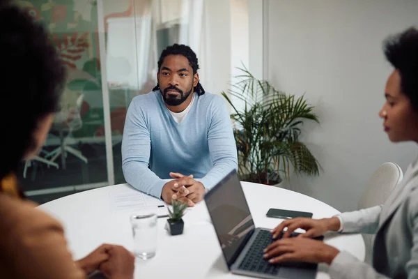 African American man talking to human resource team during job interview in the office.