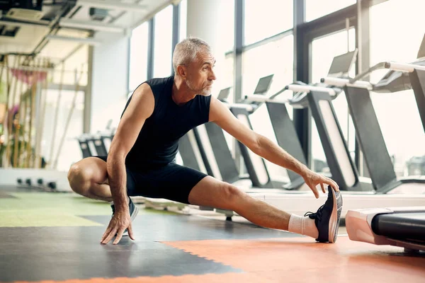 Mature Sportsman Stretches His Leg While Warming Gym — Fotografia de Stock