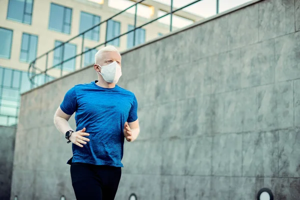 Athletic Albino Man Running City While Wearing Protective Face Mask 图库照片