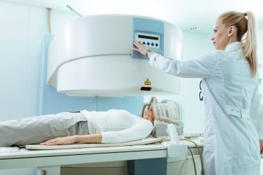 Female doctor beginning CT head scan procedure of a patient in the hospital. 