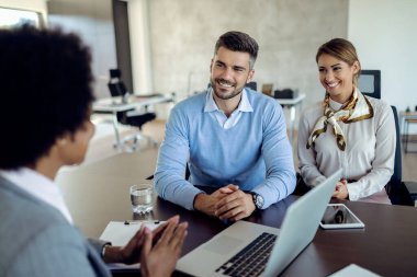 Happy couple talking to their financial consultant on a meeting in the office. 