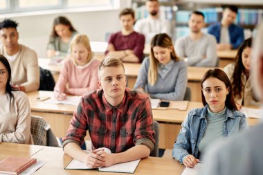 Young students listening to their professor during lecture at university classroom. 