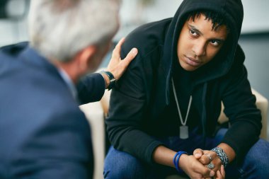 Black teenage boy having counselling with psychotherapist at mental health therapy center