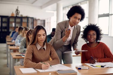 African American teacher explaining lecture to her students during class in the classroom. 