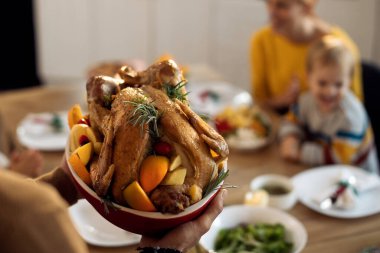 Close-up of man bringing turkey at dining table while having Thanksgiving lunch with his family. 