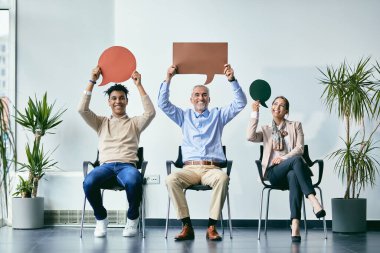 Group of happy job applicants holding speech bubbles and looking at camera while waiting for and interview. Copy space.