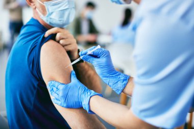 Close-up of man getting vaccinated against COVID-19 at vaccination center. 