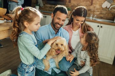 Happy parents and their daughters enjoying at home and having fun with their dog. 