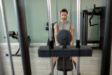 Young athletic man exercising on rowing machine during cross training in a gym.