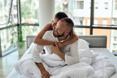 Young loving couple embracing while sitting on a bed and embracing. 