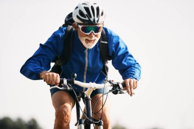 Senior athletic man cycling on mountain bike in nature. Copy space.