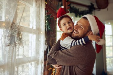 Mutlu bir baba Noel 'i evde birlikte geçirirken küçük oğlunu kucaklıyor.. 