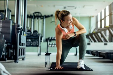Young happy athletic woman doing stretching exercises while working out at health club. 