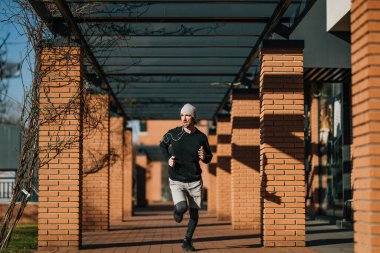 Full length of male runner jogging on the street and looking away. 